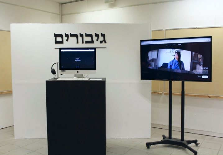 עמדת ההגשה שמכילה טלוויזיה, פודיום עם מחשב שמציג את האתר בתוכו.