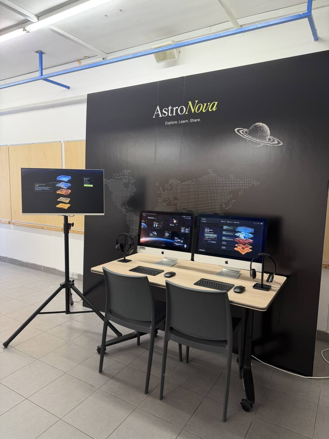 AstroNova final project exhibition booth with two computers, an additional display, headphones, and a space-themed backdrop.