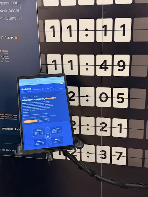 EN: A tablet mounted on the departures-board wall showing the Odysee website, headed 