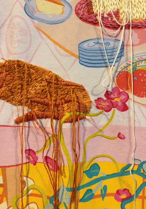 Close-up of the embroidered cat and the cake on the table.